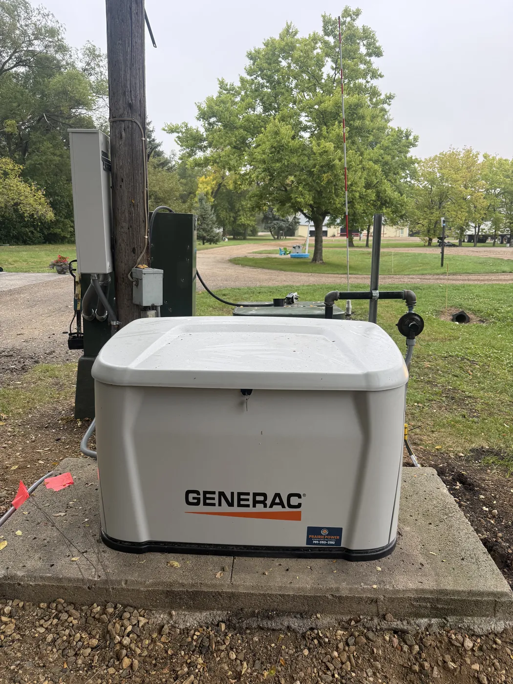 New Generac 24 kilowatt home standby generator installed on a concrete pad at a home in Wahpeton, North Dakota, with the automatic transfer switch mounted nearby