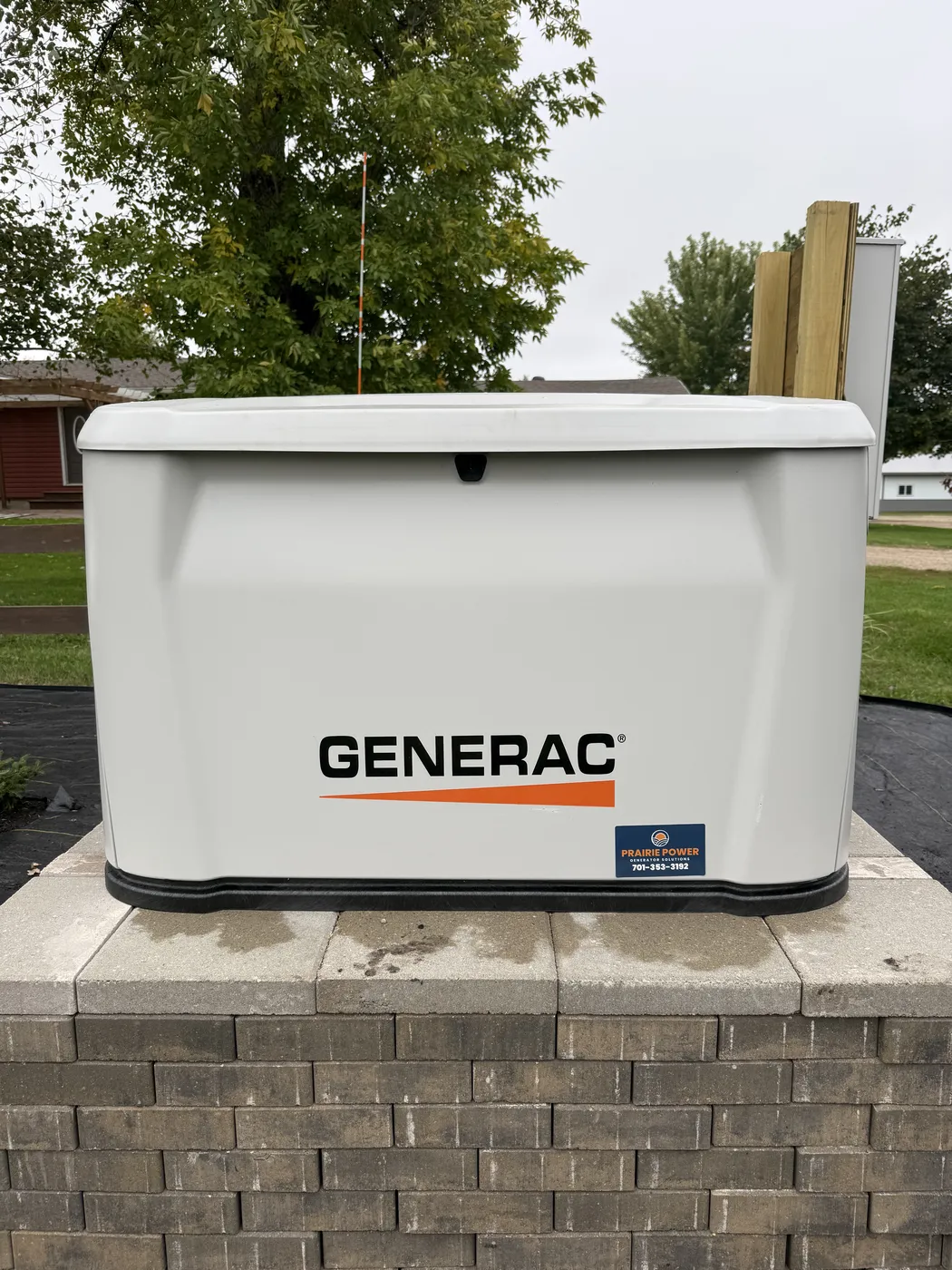 New Generac 26 kilowatt propane home standby generator installed on a raised block base at a home in Wahpeton, North Dakota